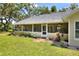 View of the screened porch with ceiling fans and furnishings, leading to the green lawn at 930 Country Oaks Ln, Lakeland, FL 33810