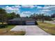 Wide driveway leading to a two-car garage, surrounded by green lawns and mature trees at 1195 E George St, Bartow, FL 33830