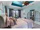Light-filled main bedroom boasts tray ceiling, ceiling fan, accent lighting, and comfortable bed at 1394 Oakmont Dr, Winter Haven, FL 33884