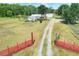 Wide shot of a property with a single Gathering home, storage sheds, and driveway framed by a red gate at 14810 Brahma Rd, Polk City, FL 33868