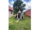 Exterior shot of a triangular wooden animal shelter with a red roofed building nearby in a grassy, rural setting at 14810 Brahma Rd, Polk City, FL 33868