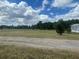 Expansive grassy lot with a dirt road in the foreground and trees visible in the distance at 14810 Brahma Rd, Polk City, FL 33868
