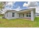 Back exterior of home with stucco walls, covered patio, and lush green grass at 1517 Leamington Ln, Winter Haven, FL 33884