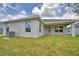 Back exterior of home with stucco walls, covered patio, and lush green grass at 1517 Leamington Ln, Winter Haven, FL 33884