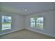 An empty, carpeted bedroom has two windows providing ample light at 1517 Leamington Ln, Winter Haven, FL 33884