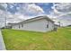 Side view of exterior of home featuring stucco walls, lush green grass and cloudy sky at 1517 Leamington Ln, Winter Haven, FL 33884