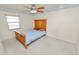 Cozy bedroom with a wooden frame bed, neutral carpet, and a ceiling fan, illuminated by natural light at 2103 Sylvester Ct, Lakeland, FL 33803