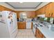 Traditional kitchen features white appliances, tile floor, and wood cabinetry at 2103 Sylvester Ct, Lakeland, FL 33803