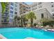 Beautiful outdoor pool area with lounge chairs surrounded by lush landscaping and a condominium building at 235 6Th Nw St # 307, Winter Haven, FL 33881