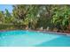 Swimming pool surrounded by lush green landscaping and foliage with lounge chairs at 235 6Th Nw St # 307, Winter Haven, FL 33881