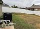View of the backyard with full white vinyl fence, pool equipment, and dry grass at 2663 Brookside Bluff Loop, Lakeland, FL 33813