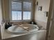 Relaxing bathtub area with tiled surround, a window with shutters, and decorative accents at 2663 Brookside Bluff Loop, Lakeland, FL 33813