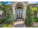 Elegant front entrance with double doors, decorative columns, and a brick walkway surrounded by lush greenery at 2743 Verandah Vue Way, Lakeland, FL 33812