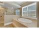 Main bathroom featuring a soaking tub, step-up tiled platform, and large window for natural light at 2743 Verandah Vue Way, Lakeland, FL 33812