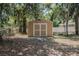 Outside view of backyard shed with double doors surrounded by trees and a white picket fence at 2933 Blackwater Oaks Dr, Mulberry, FL 33860