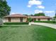 Charming brick home featuring a well-manicured lawn, mature landscaping, and an inviting driveway at 3002 Helms Dr, Auburndale, FL 33823