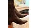 Stylish brown leather boots with laces, placed in front of a blurred living room background at 3233 Gardner Rd, Lakeland, FL 33810