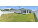 Spacious backyard with lush green grass, white vinyl fencing, and a covered patio area at 3946 Willow Ridge Dr, Lakeland, FL 33810