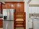 Kitchen with stainless steel refrigerator and pull-out shelves in wooden cabinetry, next to laundry room at 4193 Stone Creek Loop, Lake Wales, FL 33859