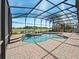A luxurious screened pool with a brick deck and serene views beyond the enclosure for outdoor enjoyment at 4193 Stone Creek Loop, Lake Wales, FL 33859