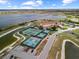 Aerial view of community tennis and pickle ball courts near lake and clubhouse, offering scenic recreation at 4193 Stone Creek Loop, Lake Wales, FL 33859