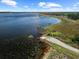 Scenic aerial view of a serene lake and a quaint boat ramp surrounded by lush greenery and clear skies at 4193 Stone Creek Loop, Lake Wales, FL 33859
