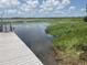 Wooden dock leading to water frontage with vibrant blue sky and green foliage in the background at 427 Longfellow Blvd, Lakeland, FL 33801