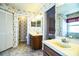 Well-lit bathroom with double sinks, wooden cabinets, wallpaper and an open doorway to a bedroom at 4976 Pleasant Hollow Trl, Lakeland, FL 33811