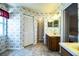 Charming bathroom featuring double sinks, wooden cabinets, wallpaper, and an open doorway at 4976 Pleasant Hollow Trl, Lakeland, FL 33811