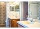 Bathroom featuring double sinks, wooden cabinets, and patterned wallpaper throughout at 4976 Pleasant Hollow Trl, Lakeland, FL 33811