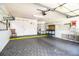 Spacious garage with ample storage, a workbench area, a rolling ladder, and gray painted floors at 4976 Pleasant Hollow Trl, Lakeland, FL 33811