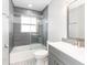 Bathroom featuring a tub with a glass door, gray cabinets and decorative floor and wall tiles at 502 Duchess Dr, Lakeland, FL 33803