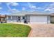 Charming single-story home with a brick-paved driveway, white garage door, and well-maintained lawn under a blue sky at 525 Eagle Run, Lakeland, FL 33809