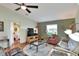 Bright living room featuring hardwood floors, a ceiling fan, a large window, and a glimpse into an adjacent bedroom at 525 Eagle Run, Lakeland, FL 33809