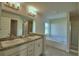 Bright bathroom features a double sink vanity, soaking tub, and glass-enclosed shower at 580 Jett Ln, Davenport, FL 33837
