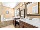 Bathroom featuring dual sinks, dark cabinetry, soaking tub, light fixtures, and tan walls at 633 Heather Glen Loop, Winter Haven, FL 33884