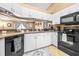 Close-up of bright kitchen featuring white cabinets, black appliances, breakfast bar, and tile flooring at 633 Heather Glen Loop, Winter Haven, FL 33884