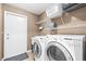 Functional laundry room features modern washer and dryer, storage shelves, and access to the backyard at 633 Heather Glen Loop, Winter Haven, FL 33884