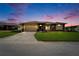 Inviting single-story home featuring a well-manicured lawn, attached two-car garage, and warm exterior lighting at 7890 Ashford Dr, Lakeland, FL 33810