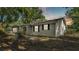 Exterior view of a gray home with classic siding, and dark-trimmed windows, situated on a wooded lot at 819 Swann Dr, Lakeland, FL 33809
