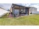 View of the backyard highlighting a screened in porch and a well-maintained lawn with white vinyl fence at 983 Revere Ave, Haines City, FL 33844