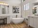 Bright bathroom featuring a soaking tub, vanity, plantation shutters, and wood-look flooring at 130 Sylvana Ct, Auburndale, FL 33823