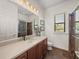Bathroom featuring a vanity, large mirror, tiled shower, and a window that brings in natural light at 130 Sylvana Ct, Auburndale, FL 33823