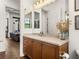 Bathroom with vanity, cabinet, mirrors, and decorative items. A living room can be seen in the adjacent room at 130 Sylvana Ct, Auburndale, FL 33823