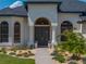 Elegant front entrance featuring double doors, decorative columns, and beautifully landscaped flowerbeds at 130 Sylvana Ct, Auburndale, FL 33823