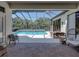 Covered patio featuring brick pavers, a dining set, and a screen enclosure overlooking the inviting pool at 130 Sylvana Ct, Auburndale, FL 33823