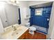 Bathroom featuring tiled shower, wood-look floors, vanity sink, and blue walls at 137 Leitha Way, Lakeland, FL 33809
