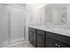Modern bathroom with dual sinks, dark cabinets, and a glass-enclosed shower at 1424 Portmore Dr, Mulberry, FL 33860