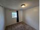 Bedroom with wall to wall carpet, standard ceiling light fixture and a single window with dark curtains at 1809 Optimist Dr, Lakeland, FL 33801