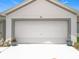 Close-up of the garage door with potted plants, offering convenient two-car parking at 1821 Thompson Preserve Boulevard, Bartow, FL 33830